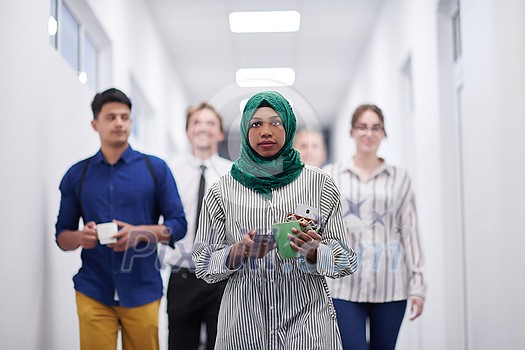 multi-ethnic startup business team walking through the hallway of the building while coming back from a coffee break