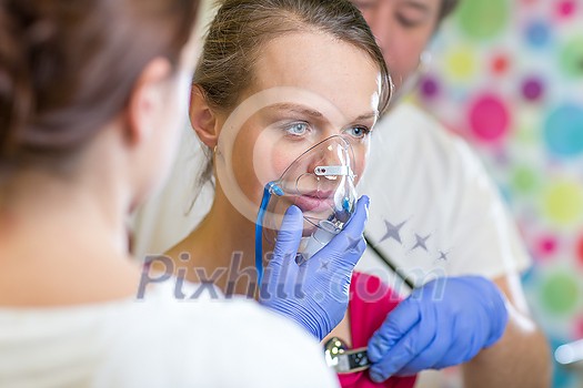 Pretty, young woman being taken care of by medics in a hospital - udergoing a check, getting oxygen Pretty, young woman being taken care of by medics in a hospital - udergoing a check, getting oxygen