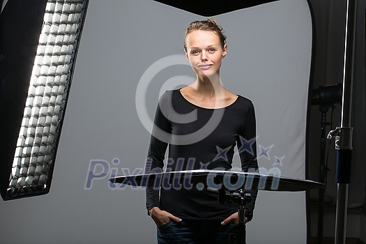 Beautiful female model posing in a photographic studio surrounded by professional strobe lights