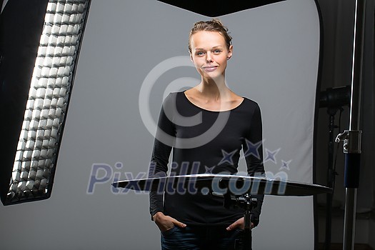 Beautiful female model posing in a photographic studio surrounded by professional strobe lights Beautiful female model posing in a photographic studio surrounded by professional strobe lights