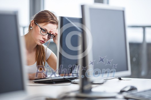 Pretty, female student looking at a desktop computer screen, learning unpleasant news about her exam results. University/office/school concept Pretty, female student looking at a desktop computer screen, learning unpleasant news about her exam results. University/office/school concept