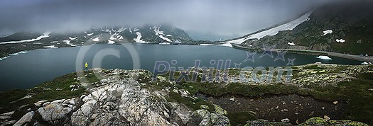 Young admiring the natural beauty of a glaciar lake in Swiss Alps - Panoramic image Young admiring the natural beauty of a glaciar lake in Swiss Alps - Panoramic image