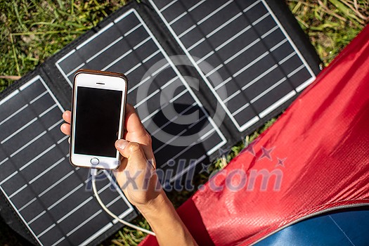 Cell phone charging with a solar charger in a tent during an outdoor trip