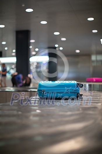 Arrived luggage going around on a conveyor belt waiting to be claimed at the baggage claim zone at a modern international airport