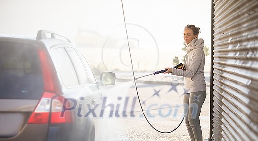 Woman washing her car in a manual carwash (color toned image)
