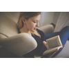 Cute young woman reading a book in a designer chair - color toned image, shallow DOF