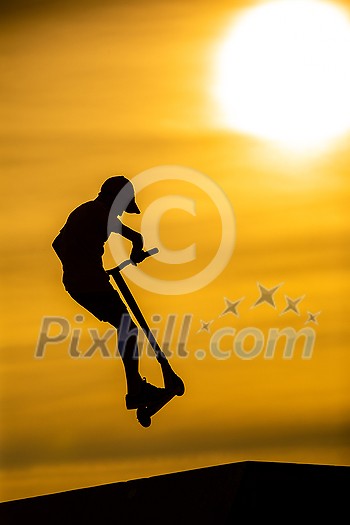 Silhouette of a young boy riding a scooter against the background of a sea sunset Silhouette of a young boy riding a scooter against the background of a sea sunset