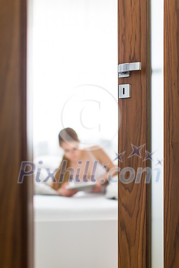 Beautiful young woman in her bed,  using a tablet computer in the morning