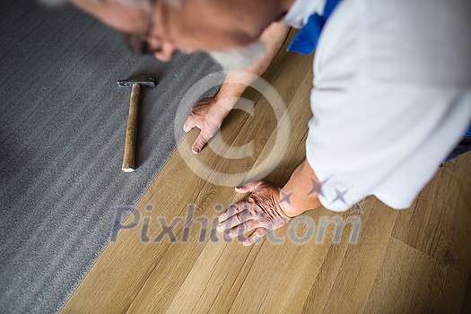 DIY, repair, building and home concept - close up of male hands lying parquet floor board/laminate flooring (shallow DOF; color toned image) DIY, repair, building and home concept - close up of male hands lying parquet floor board/laminate flooring (shallow DOF; color toned image)