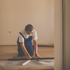 DIY, repair, building and home concept - senior man lying parquet floor board/laminate flooring (shallow DOF; color toned image)