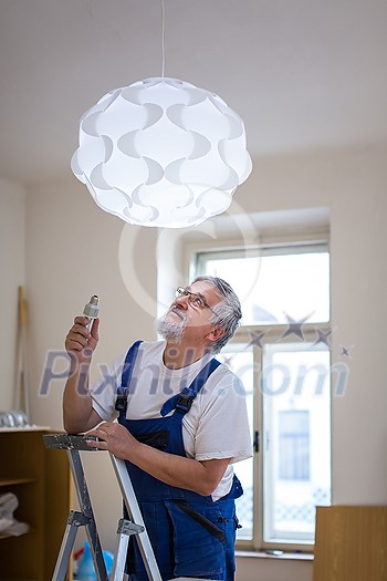 DIY, repair, building and home concept - Senior landlord hanging a new light in a rental appartement (shallow DOF; color toned image) DIY, repair, building and home concept - Senior landlord hanging a new light in a rental appartement (shallow DOF; color toned image)