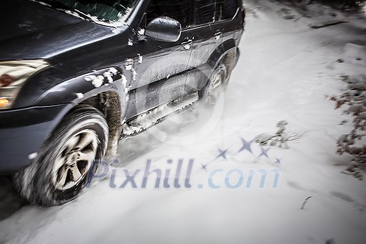 Motion blurred image of a big suv car going fast on a snow covered forest road