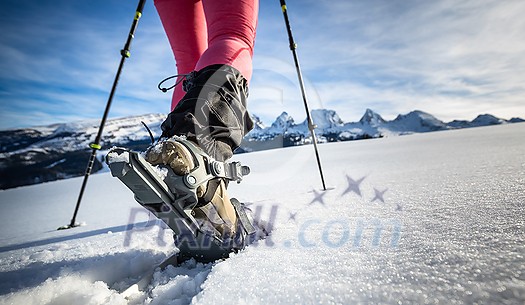Young woman snowshoeing in high mountains, enjoying a lovely day