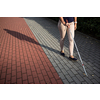 Blind woman walking on city streets, using her white cane to navigate the urban space better and to get to her destination safely