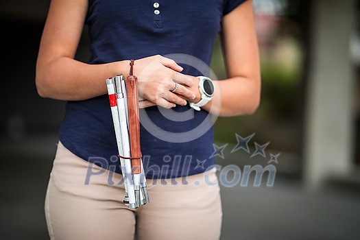 Blind woman walking on city streets, using her white cane to navigate the urban space better and to get to her destination safely Blind woman walking on city streets, using her white cane to navigate the urban space better and to get to her destination safely