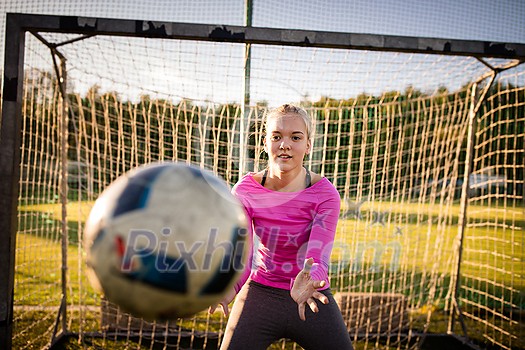 Teen female goalie catching a shot during a soccer game