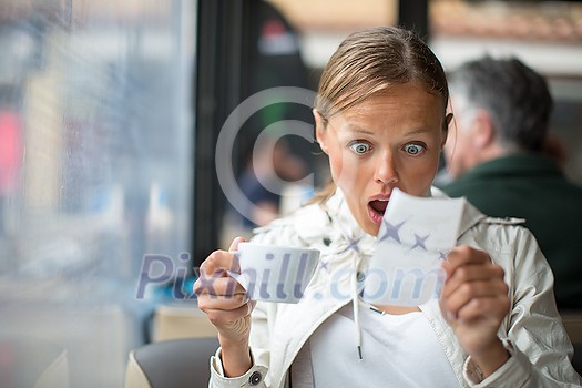 Pretty, young woman baffled with the bill in a coffeeshop/restaurant Pretty, young woman baffled with the bill in a coffeeshop/restaurant