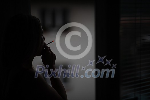 Mid-aged woman lighting a cigarette at home, getting her nicotine daily dose Mid-aged woman lighting a cigarette at home, getting her nicotine daily dose