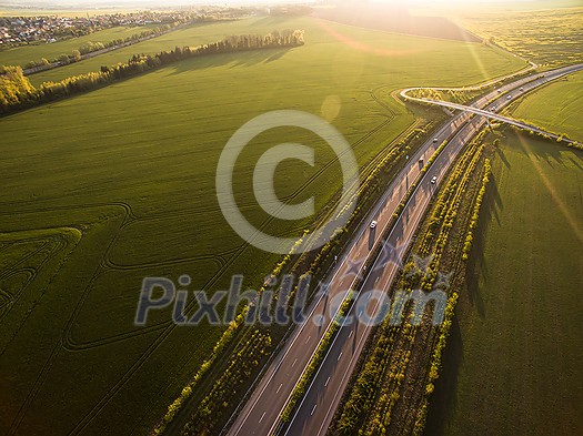 Aerial view of a highway amid fields with cars on it Aerial view of a highway amid fields with cars on it
