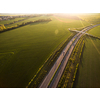 Aerial view of a highway amid fields with cars on it