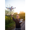 Pretty, young woman flying a drone quadcopter outdoors, taking aerial photos and footage with it