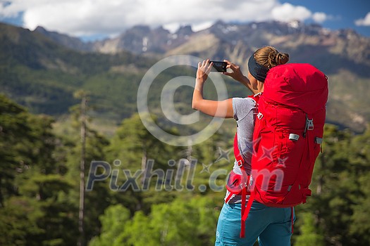 Pretty, female hiker in high mountains packing her backpack