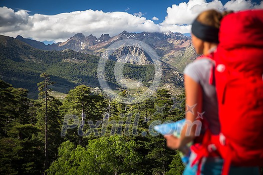 Pretty, female hiker in high mountains packing her backpack