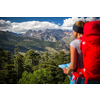 Pretty, female hiker in high mountains packing her backpack