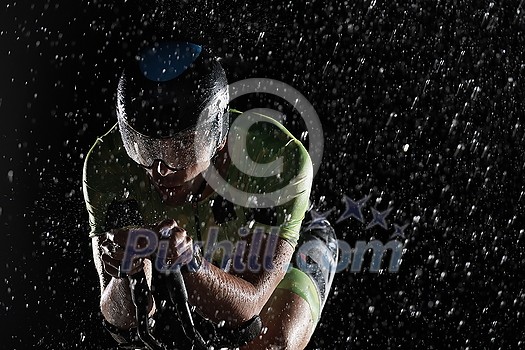 triathlon athlete riding professional racing bike fast  at night with bad weather and falling rain