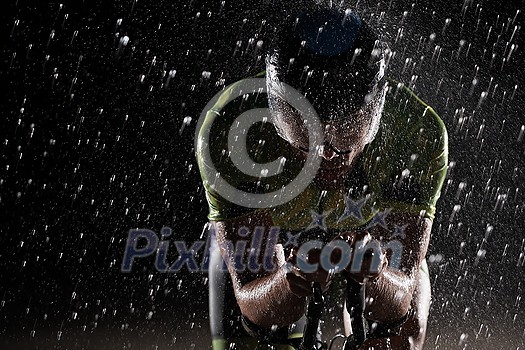 triathlon athlete riding professional racing bike fast at night with bad weather and falling rain triathlon athlete riding professional racing bike fast at night with bad weather and falling rain