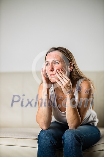 Mid-aged woman touching her cheek/mouth with painful expression because of toothache/dental issue