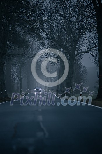 Modern SUV car on a misty, alpine road, going fast towards the camera