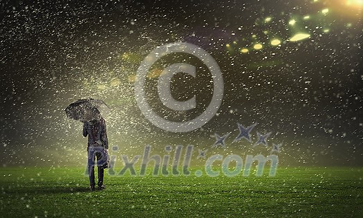Back view of businessman with umbrella standing under rain