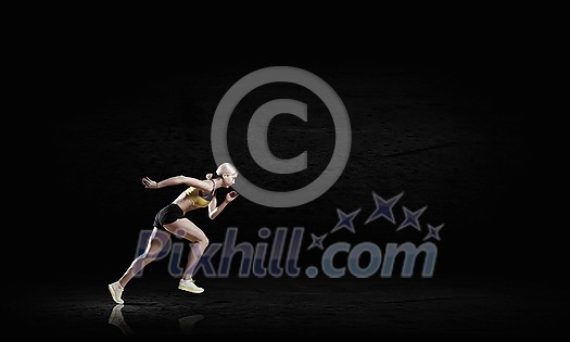 Young woman athlete running fast on dark background Young woman athlete running fast on dark background