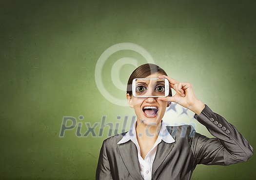 Beautiful young woman holding mobile phone against her eyes Beautiful young woman holding mobile phone against her eyes