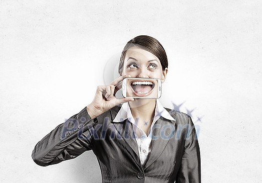 Beautiful young woman holding mobile phone against her mouth and smiling Beautiful young woman holding mobile phone against her mouth and smiling