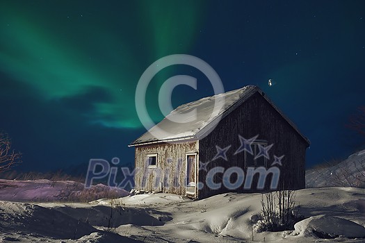 Traditional Norwegian fisherman's cabins  northern Norway. Winter season bad weather at night with northern lights aurora borealis