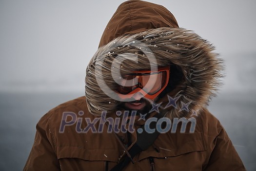 portrait local authentic eskimo  man at winter in stormy weather wearing warm  fur jacket