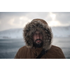 portrait local authentic eskimo  man at winter in stormy weather wearing warm  fur jacket