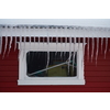 Icicles on the roof of a red house in Norway. melting icicles. natural ice formation in winter time.