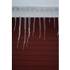 Icicles on the roof of a red house in Norway. melting icicles. natural ice formation in winter time.