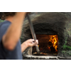 Cook baking pizza in a traditional stone wood fired oven