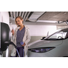Young woman charging an electric vehicle in an underground garage equiped with e-car charger. Car sharing concept.