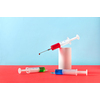 Creative healthcare composition of two plastic disposable syringes with blue and green drugs and one with drop of red liquid on a plaster cylinder on a duotone background, copy space.