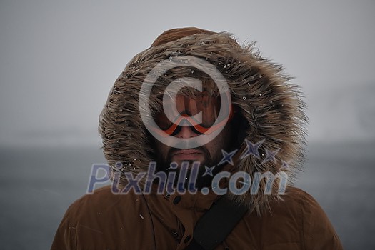 portrait local authentic eskimo  man at winter in stormy weather wearing warm  fur jacket