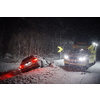 car accident on slippery winter road at night with heavy snow fall and paramedic ambulance first aid car