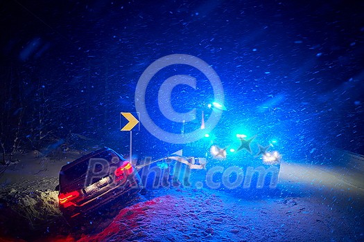 car accident on slippery winter road at night with heavy snow fall and paramedic ambulance first aid car