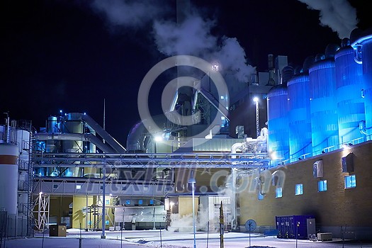 Factory at Night Atmospheric Environmental Air Pollution From Industrial Smoke. Pipes Steel Tank Plant Wood and Paper  Production. Thick Smoke and Steam.