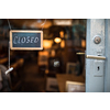 Closed - sign hanging on glass door of a shop in a city