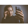 Young woman holding a phone, tired and exhausted, blue light straining her eyes, messing up her circadian rhytm